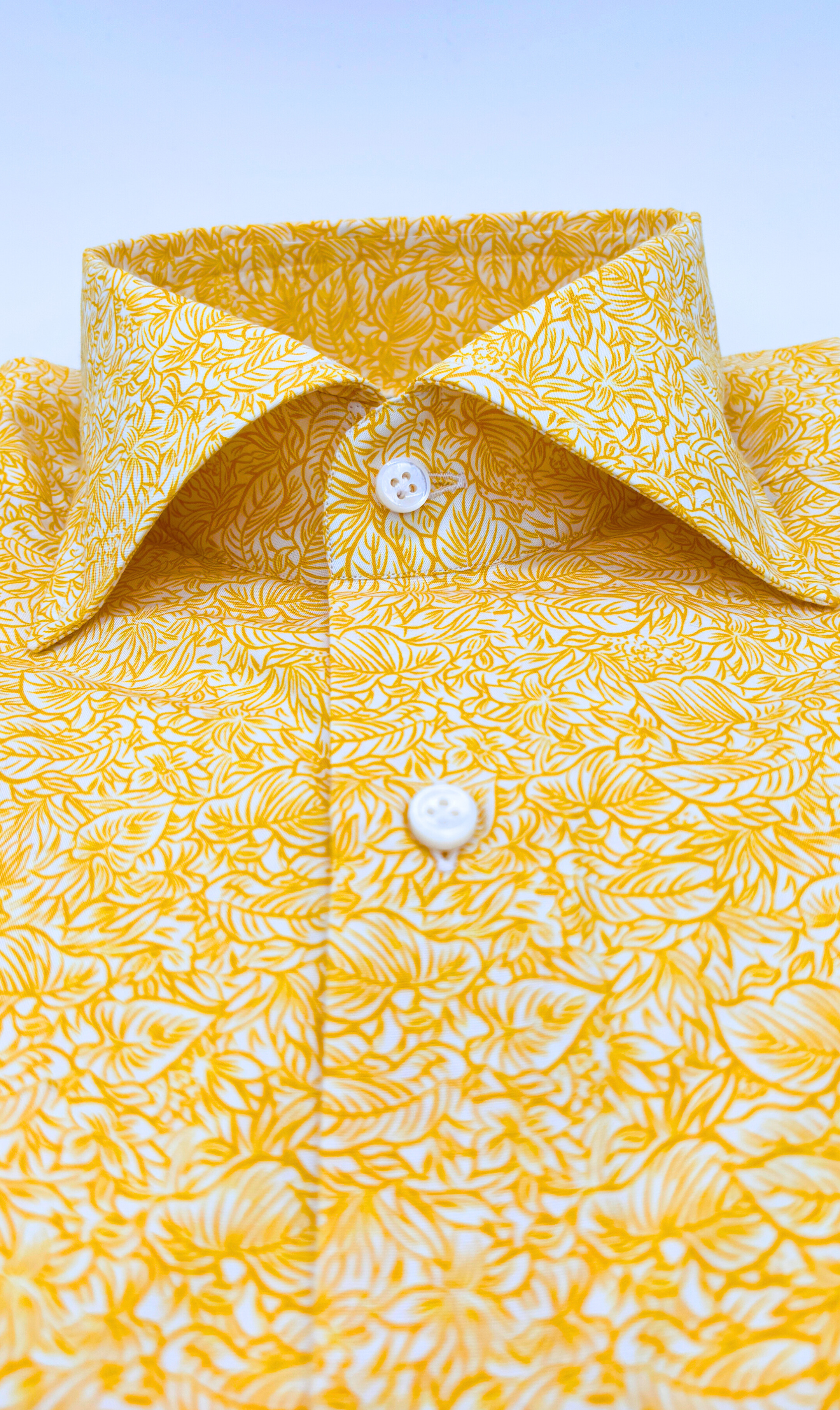 Detailansicht des Softcollar-Kragens und der runden Manschetten des nachhaltigen Herrenhemds mit gelben Palmen Muster.